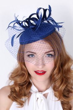 Be the envy of the party in this elegant felt fascinator. The round felt base is covered with satin ribbon loops, adorned with flighty feathers and topped off with a birdcage veil. This gorgeous piece is perfect for any special occasion. - Easy wear headband - Optional; tuck-a-way veil - Available in several other colors Ribbon Veil, Felt Fascinator, Navy Blue Fascinator, Bridal Birdcage Veils, Ivory Fascinator, Sinamay Hat, Blue Fascinator, Happy Hat, Derby Fascinator