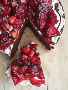 a chocolate cake with strawberries on top and one slice cut out from the cake