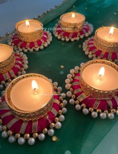 some candles are sitting on a table with beads and pearls around them, all lit up