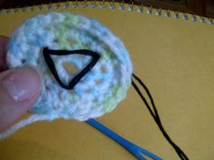 a crocheted object is being held by someone's hand with scissors in front of it