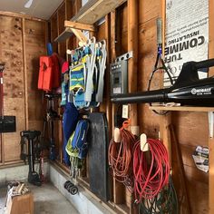 there are many skis and snowboards hanging on the wall in this garage area