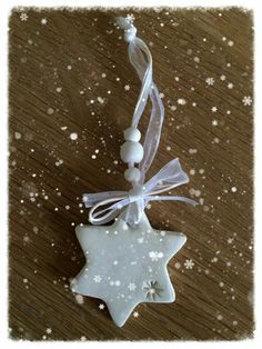 a white star ornament hanging from a string on top of a wooden table