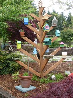 a wooden tree with many bird houses on it's branches in a garden area