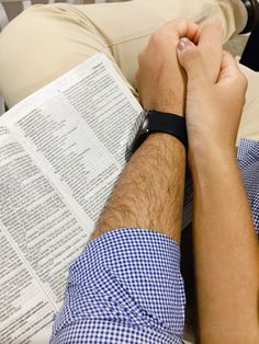 a man laying on top of a bed next to an open book with his hands folded