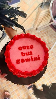 a red cake with the words cute but gomini written on it