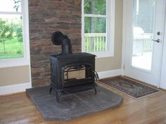 a stove sitting in the middle of a living room next to a door and window