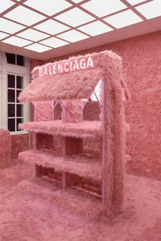 a room with pink carpet and shelving in the shape of a bookcase that reads balenocaga