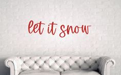 a white leather couch sitting in front of a wall with the words let it snow on it