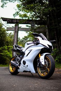 a white and yellow motorcycle parked on the side of a road next to some trees