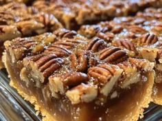 several pecan bars are stacked on top of each other in a glass dish, ready to be eaten