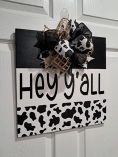 a black and white sign that says hey y'all with a cow print bow