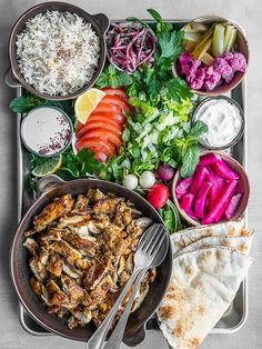 an assortment of food is displayed on a tray with utensils and spoons