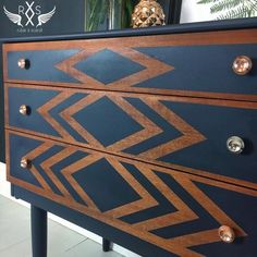 a blue and brown chest of drawers sitting on top of a white floor next to a plant