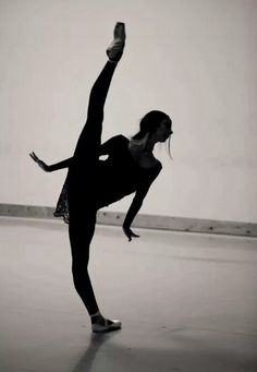 a woman doing a trick on a skateboard in the middle of an empty room