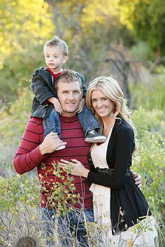 a man, woman and child are standing in the tall grass with their arms around each other