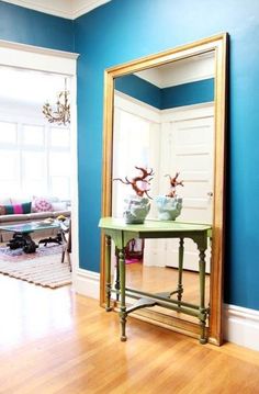 a large mirror sitting on top of a wooden floor next to a table with vases