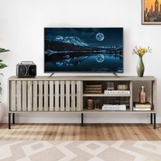 a flat screen tv sitting on top of a wooden entertainment center next to a potted plant