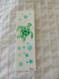 a green turtle painted on top of a piece of paper next to a white sheet