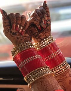 a woman's hands with henna and bracelets on her wrist, in front of a car window