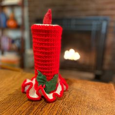 a crocheted christmas candle holder sitting on top of a table next to a fireplace