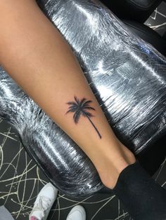 a woman's foot with a small palm tree tattoo on the left side of her leg