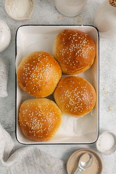 three buns with sesame seeds in a white dish