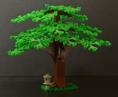 a lego tree with green plastic letters on it's trunk and branches, in front of a gray background