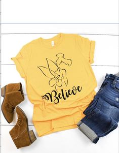 a yellow shirt that says believe next to some jeans