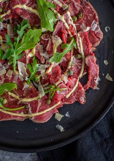 beef carpaccioo, anchovy aioii on a black plate