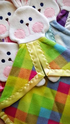 several baby bibs and mittens laid out on a bed together, including one with a teddy bear in the middle