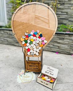 a wooden box filled with lots of small candies next to a cardboard hot air balloon