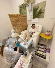 two women sitting on chairs in a living room, one is using a hair dryer