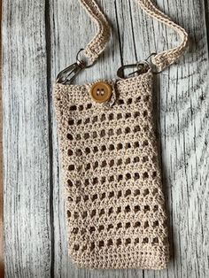 a crocheted cell phone case with a button on the front and strap around it