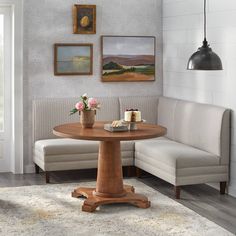 a corner table in a living room with two chairs and a bench next to it