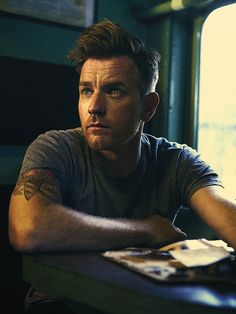 a black and white photo of a man sitting at a table with his arms crossed