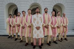 a group of men standing next to each other in front of a white and pink building