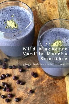 two glasses filled with blueberry vanilla matcha smoothie on top of a wooden table