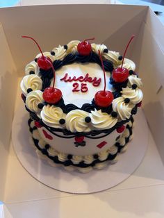 a birthday cake in a box with cherries on it and the number twenty five