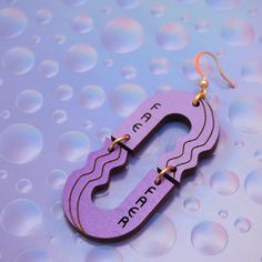 Pronoun earrings in a wavy hoop style with a light lavender and purple palette, customizable with your pronoun(s). SOLD AS A SINGLE EARRING so you can mix and match or rock just one! Eco-friendly hardwood is stained by hand with hints of woodgrain visible (colors may vary on your screen/device). View other color options: www.etsy.com/shop/wildfancydesign/?etsrc=sdt&search_query=wavy+hoop+pronoun DETAILS * About 2.25in long (6cm) but lightweight! * SOLD AS SINGLES. * Comes with a gold plated earhook. To request a different hook, include an Order Note with one of these options: silver plated hook, sterling silver hook, 14K gold fill hook, niobium hook, brass leverback.All are 100% lead free and considered nickel free by jewelry industry standards, but if you have extreme nickel sensitivity o Queer Liberation, Purple Palette, Trans Pride, Light Lavender, Gold Polka Dots, Single Earring, Raw Brass, Unique Pieces, Jewelry Earrings Dangle