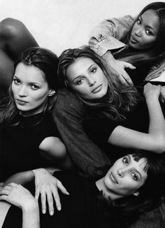 four women laying on the floor with their arms around each other and looking at the camera