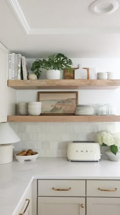 a kitchen with white cabinets and open shelving above the countertop is filled with dishes