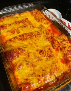 a casserole dish with cheese and sauce in it sitting on a stove top