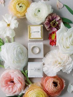 an arrangement of flowers and wedding rings on a table