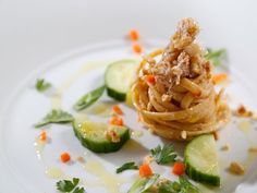 a white plate topped with pasta and cucumbers