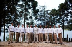 a group of men standing next to each other on top of a dirt field near trees