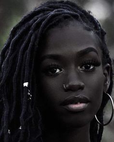 a close up of a person with dreadlocks and piercings on her nose