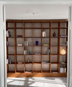 an open bookcase with many books on it in a room that has white walls and wooden floors