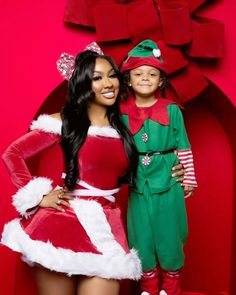 a woman and child dressed up in christmas costumes standing next to each other on a red background