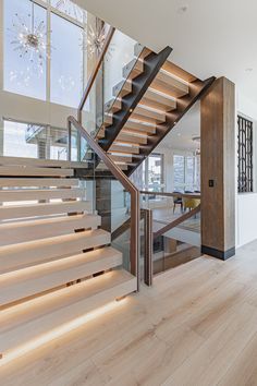 a wooden staircase in a modern home with glass railings and light wood flooring