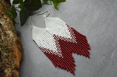 a pair of red and white beaded earrings sitting on top of a tree branch